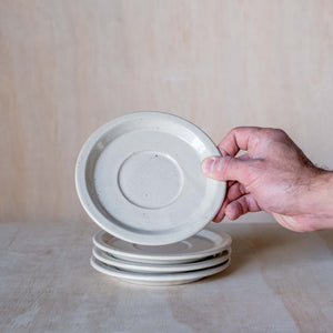 Stack of hand made ceramic saucers, beige coloured glaze