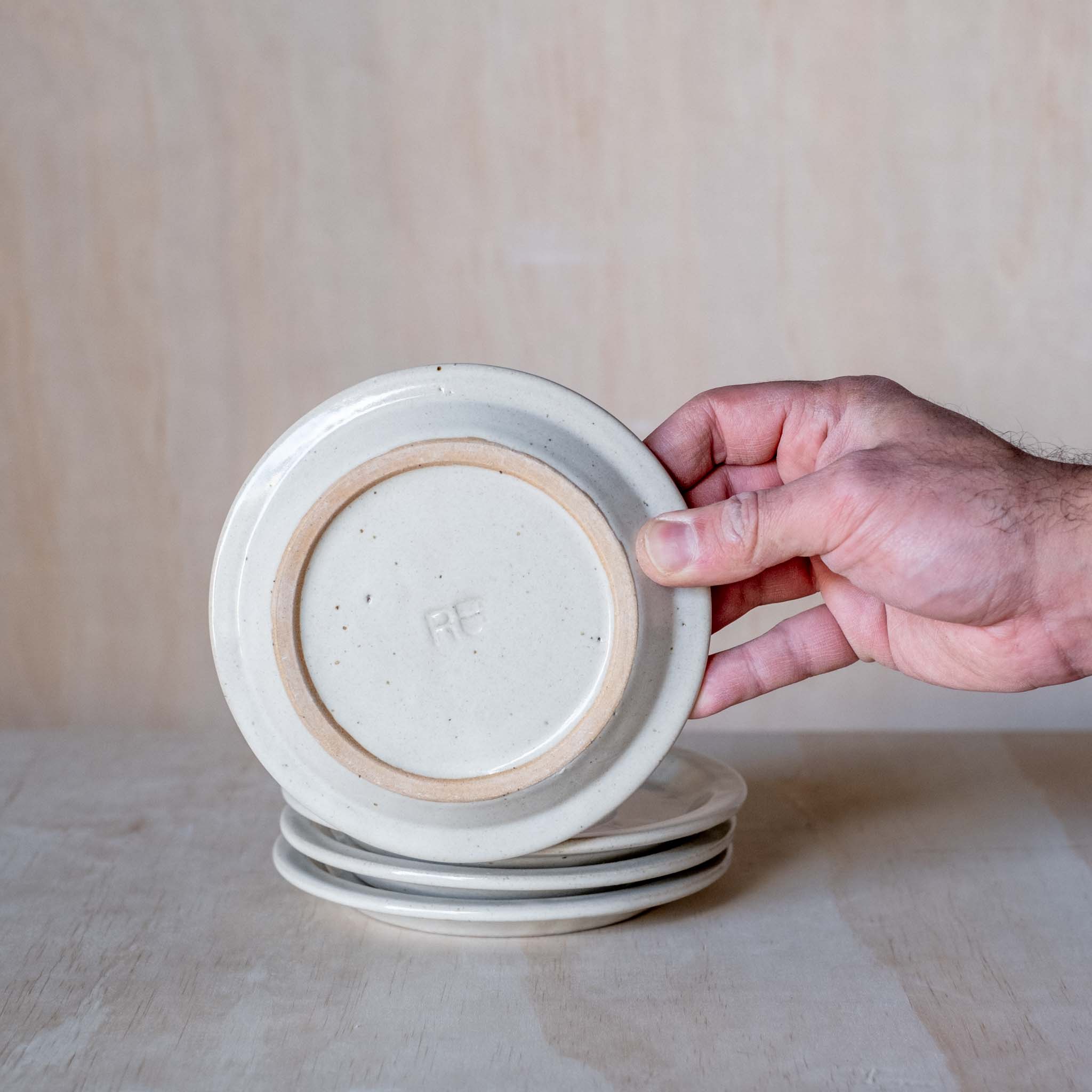 Stack of hand made ceramic saucers, beige coloured glaze