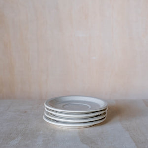 Stack of hand made ceramic saucers, beige coloured glaze